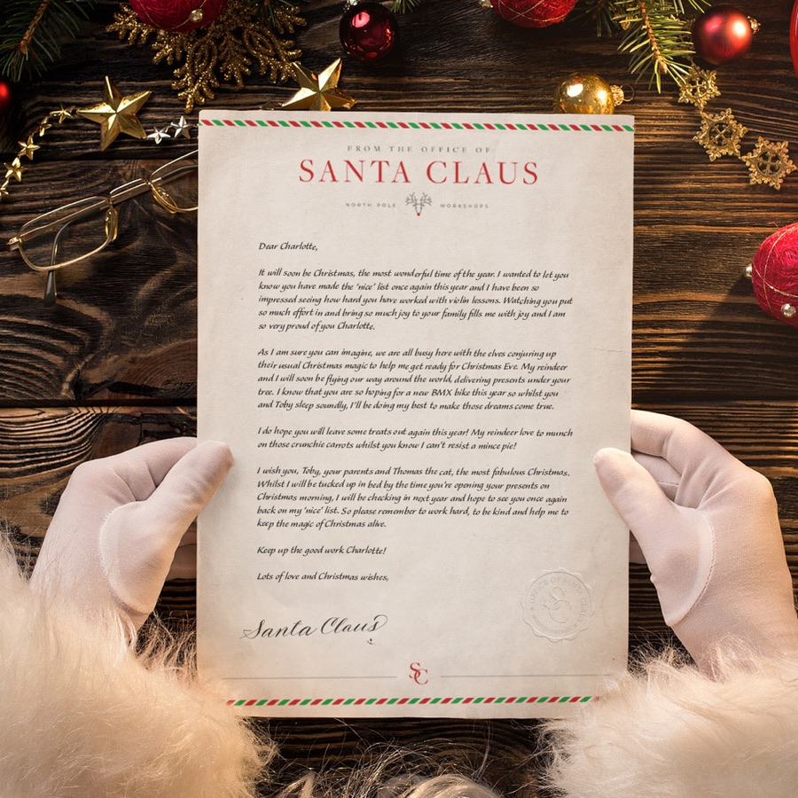 A letter from Santa on cream paper, held in white gloves
